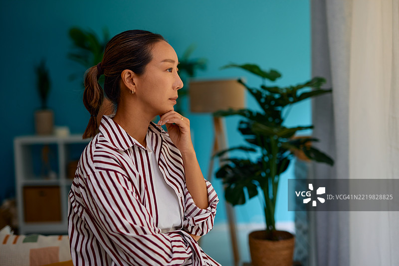 沉思的年轻女性在家中望向窗外图片素材