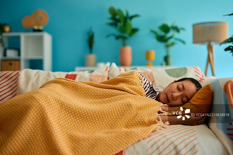 年轻女性在现代客厅的舒适沙发上安静地睡着。图片素材