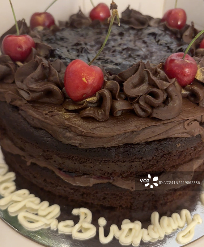 终极巧克力蛋糕。奢华有机巧克力蛋糕的特写。美味的三重巧克力生日蛋糕。英格兰2025年5月的黑森林蛋糕，配有牛奶巧克力和黑巧克力糖霜，以及光滑的新鲜樱桃。图片素材