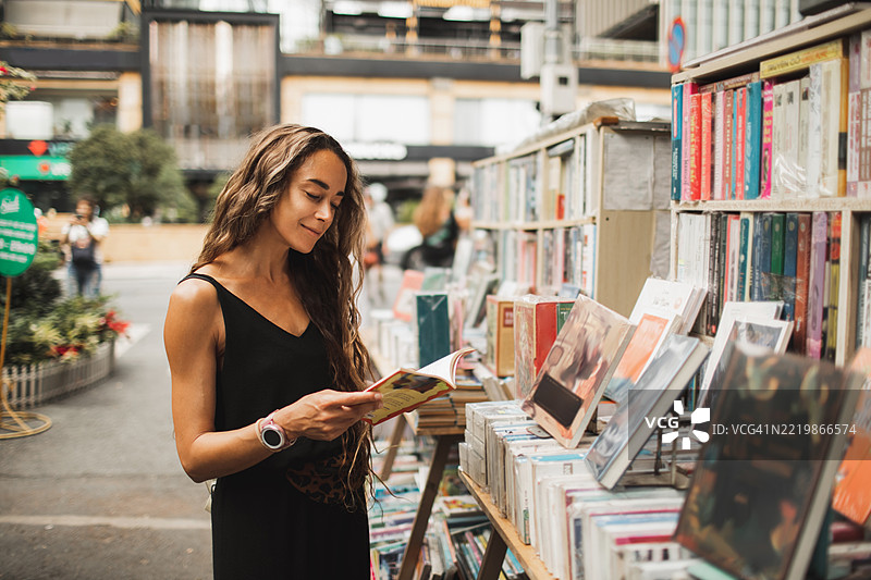 女性在城市环境中的户外书店阅读书籍图片素材