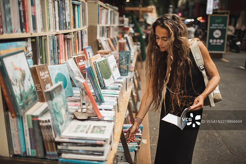 一位女性在城市的户外书市浏览书籍图片素材