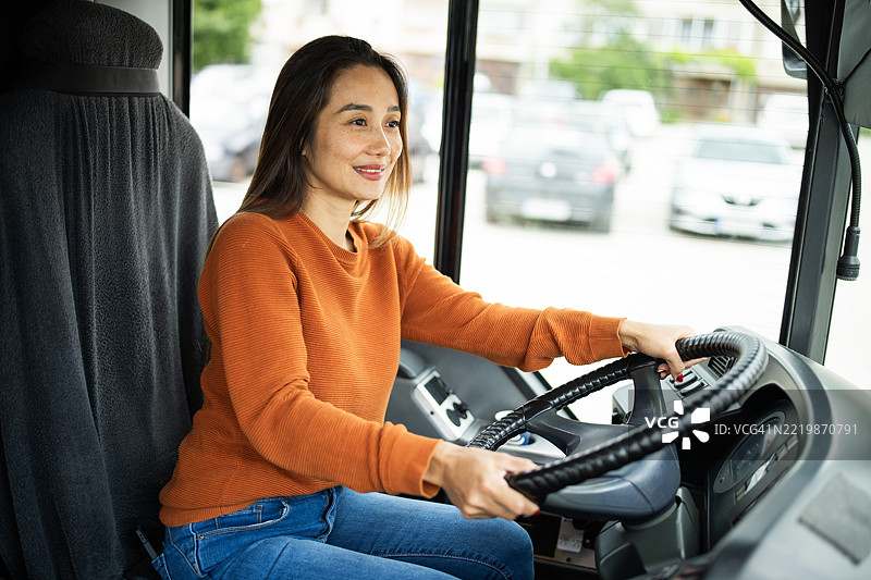 快乐的亚洲女性驾驶城市公交车。图片素材