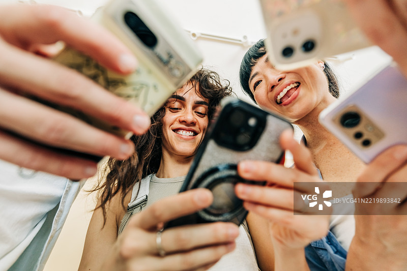 多种族的商务人士在现代办公室一起使用手机。图片素材