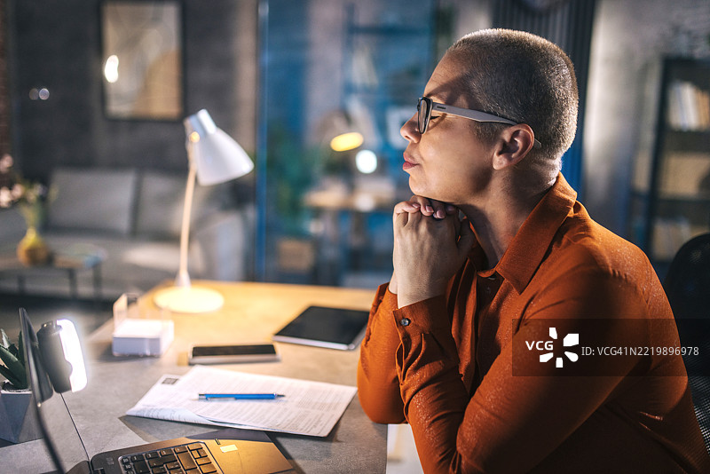 一位在深夜工作时使用笔记本电脑的疲惫女商人图片素材