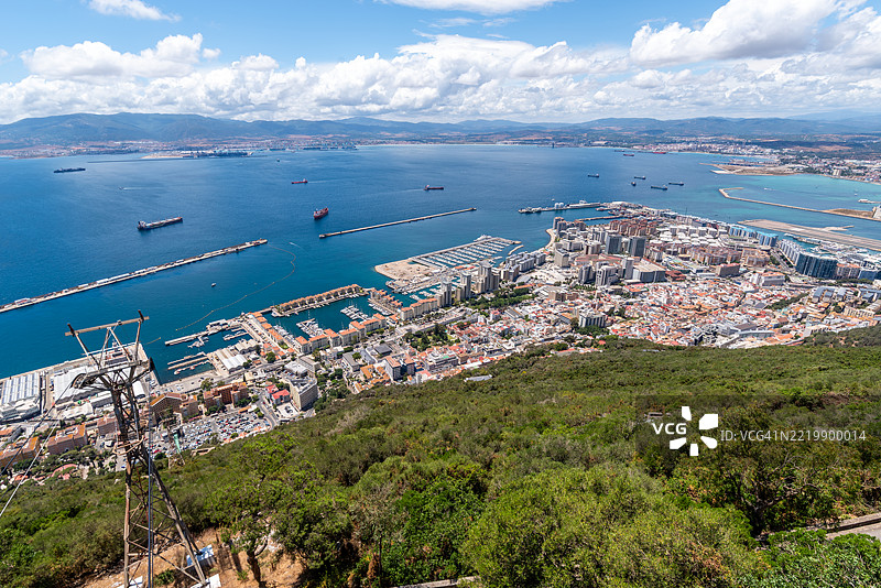 从直布罗陀岩石的视角俯瞰城市全景，展现港口、机场和郁郁葱葱的绿地，地中海的水域延伸至海峡的广阔地平线。图片素材