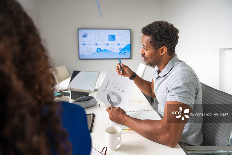 多元化的商业专业人士在现代会议室中合作，屏幕上显示着分析图表图片素材
