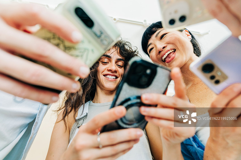 多种族的商业人士在现代办公室一起使用手机。图片素材