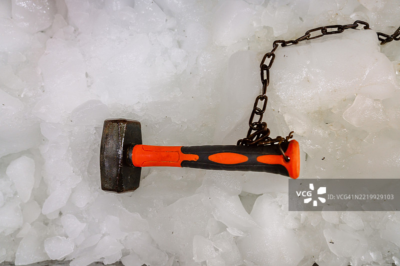 橙色手柄和金属链的大锤放在伊拉克的冰面上。图片素材