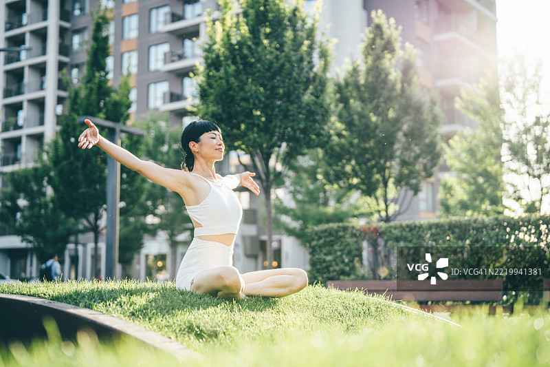 一位女性在周末的早晨，在公园的瑜伽课上冥想。图片素材