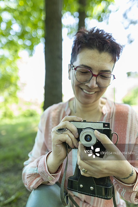 成熟的女士用她的老相机探索胶卷摄影。图片素材
