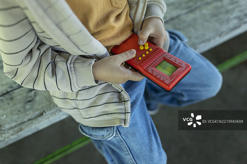 男孩坐在长椅上玩游戏。特写照片图片素材