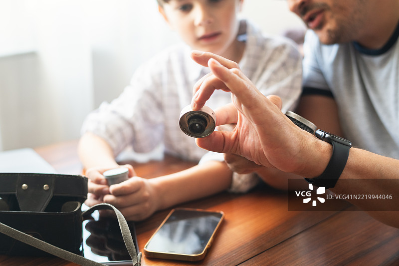 父亲向儿子展示一台老式复古相机图片素材