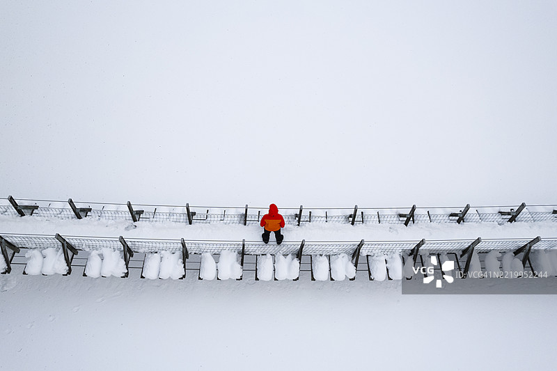 在芬兰，一名人士走过一座木桥，穿越冰冻的河流。图片素材
