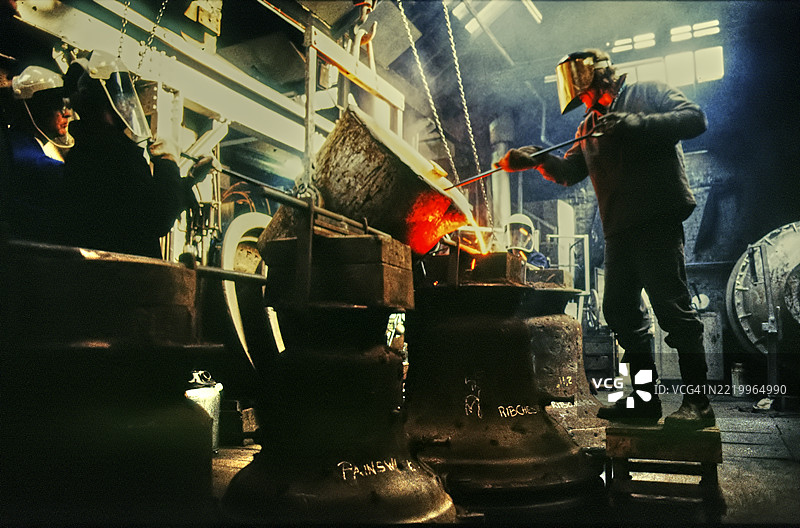 一名炉工在伦敦的教堂钟铸造厂倾倒熔融金属图片素材