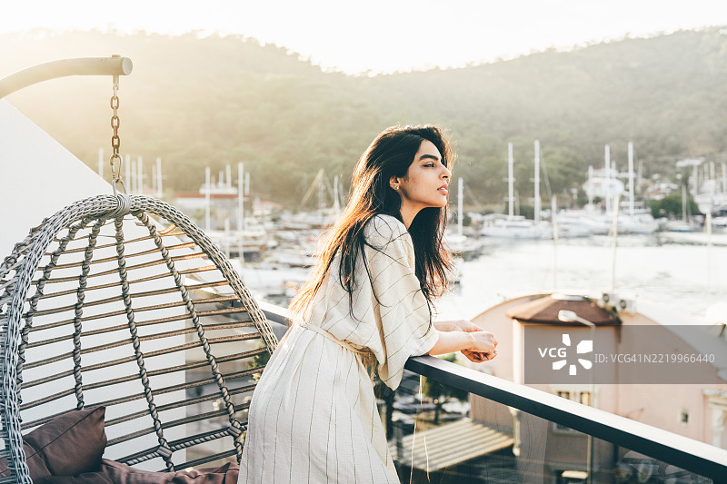 美丽的女人在阳台上享受海景的清晨。图片素材