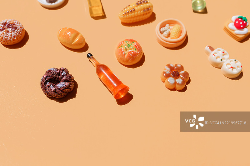 橙色背景上散落的食品和饮料玩具图片素材