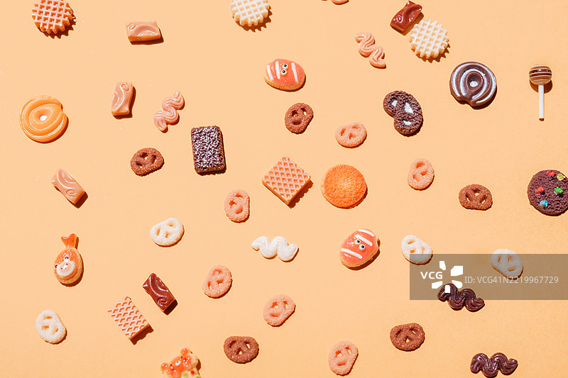 饼干、糖果和饼干散落在橙色背景上图片素材