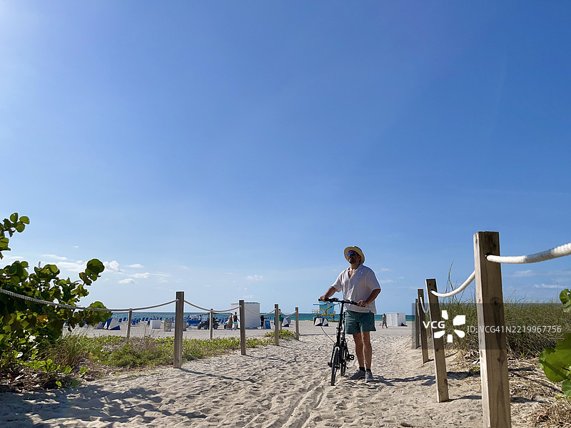 游客在阳光明媚的日子里骑着自行车漫步于迈阿密海滩图片素材