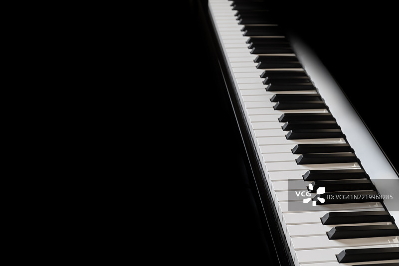 黑色背景下的钢琴和钢琴键盘。图片素材