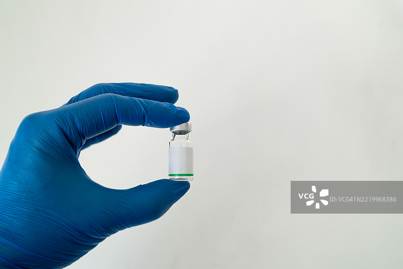 手中握着疫苗瓶，背景为白色。图片素材