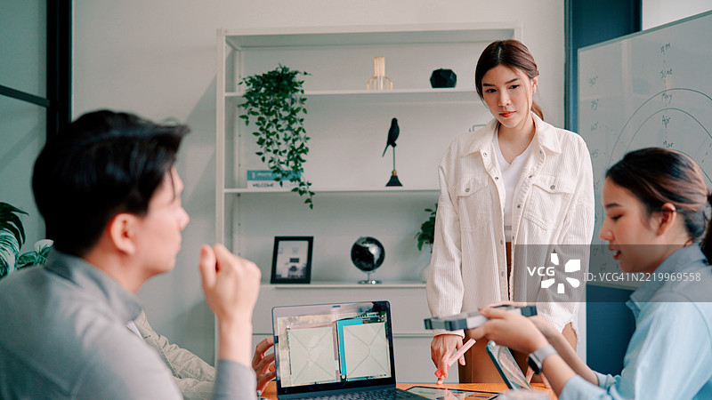 年轻的亚洲男女在会议室开会讨论下个季度的策略。图片素材