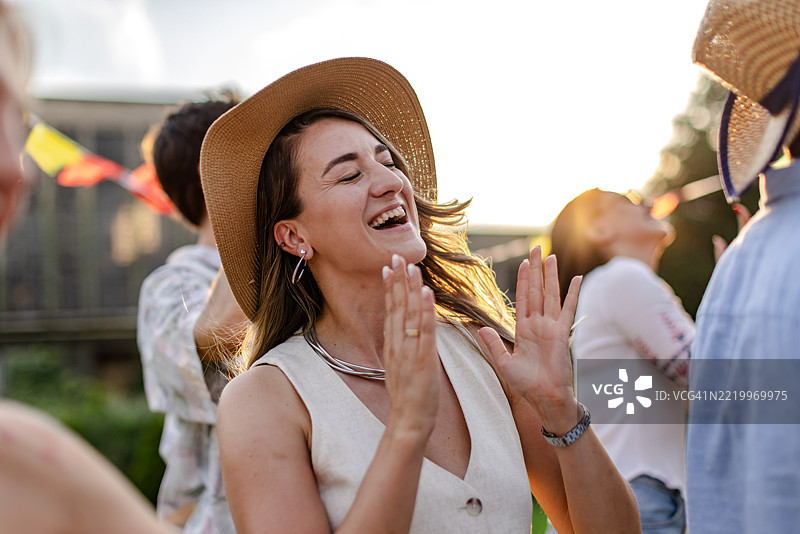 年轻人们在日落时分的户外音乐节上庆祝生活，伴随着舞蹈和欢笑。图片素材