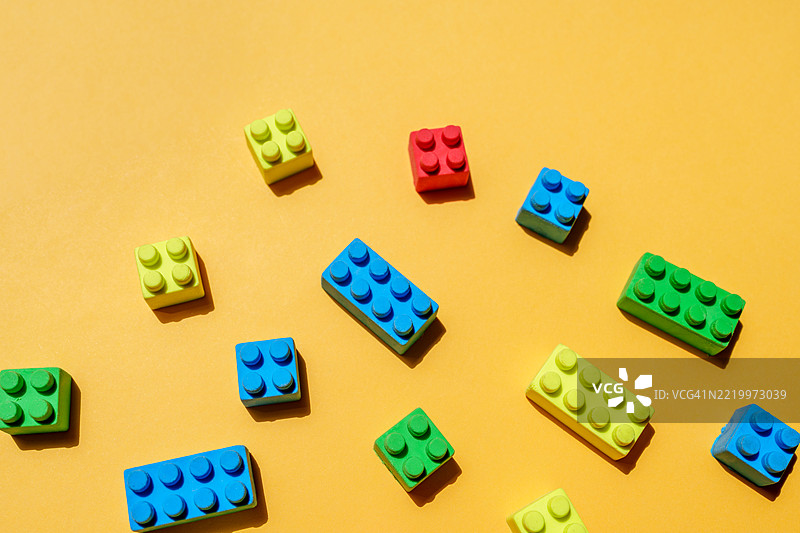 五颜六色的积木散落在黄色背景上，营造出一个充满趣味的场景图片素材