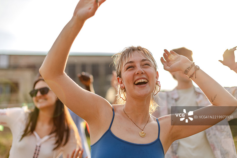 年轻人在日落时分的户外音乐节上共同庆祝，跳舞并享受热烈的氛围图片素材