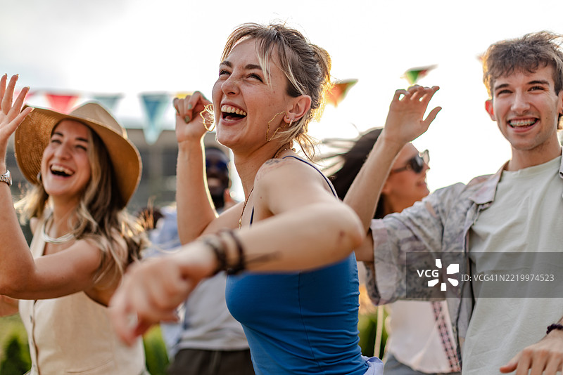 年轻人在日落时分享受充满活力的户外音乐节，尽情舞蹈和庆祝。图片素材