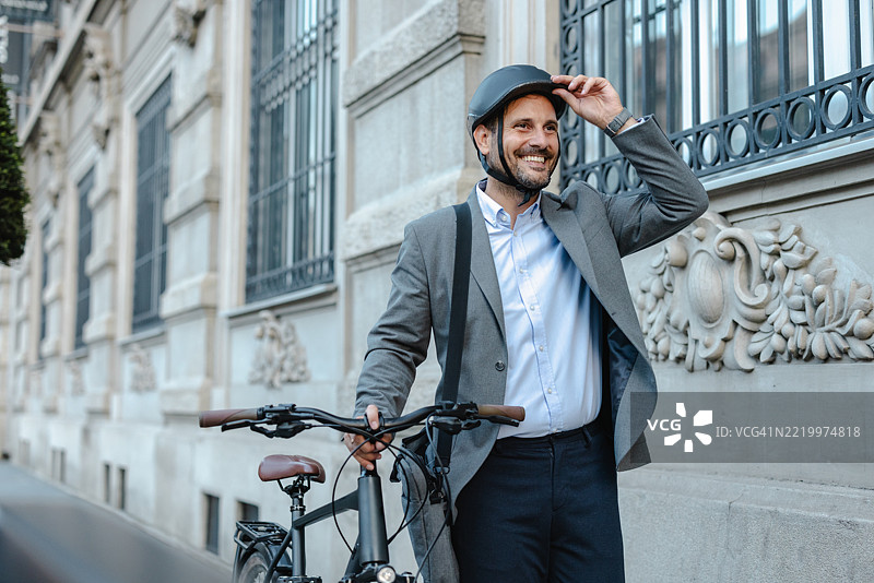 身穿正式服装和头盔的商人骑自行车通勤上班图片素材
