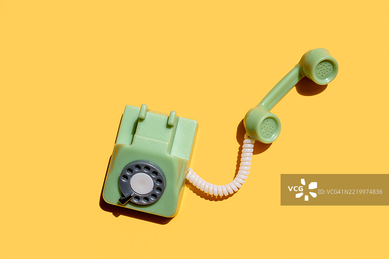 绿色复古旋转电话放在黄色背景上图片素材