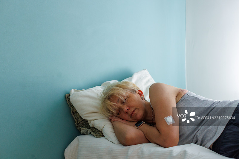 中年女性在休息，手臂上贴着医疗贴片图片素材