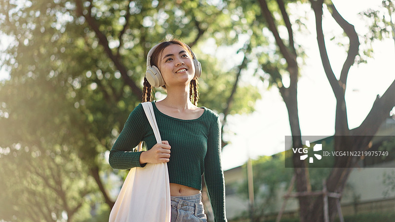 青少年悠闲地走路时听音乐。图片素材
