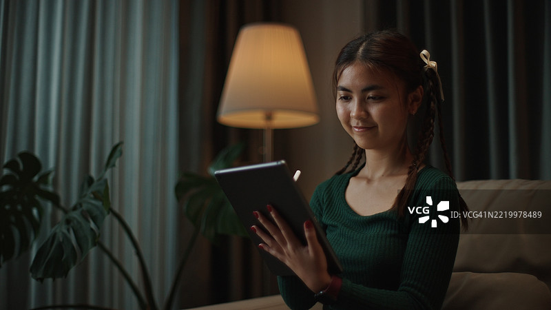 亚洲女性在夜间使用平板电脑绘画。图片素材