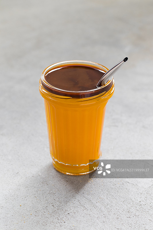 南瓜咖啡奶昔，杯中配有吸管，背景为浅灰色。图片素材