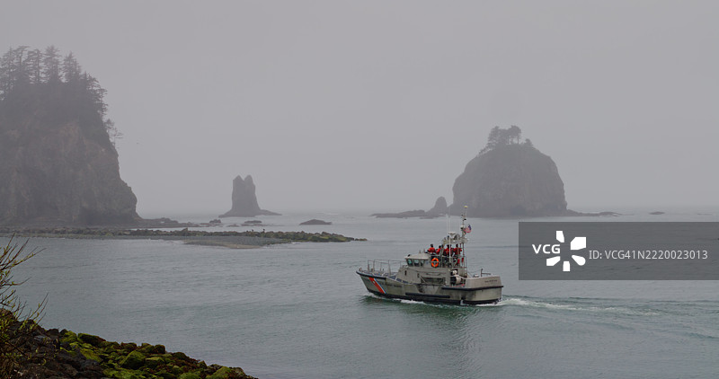 奎利特码头的地平线上点缀着巨石和一艘渔船，位于华盛顿州拉普什。图片素材