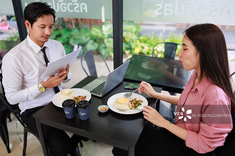 两位亚洲商务专业人士在现代餐厅进行轻松的午餐会议。捕捉工作场所文化、合作与职业网络的精髓，展现午间休息时光。图片素材