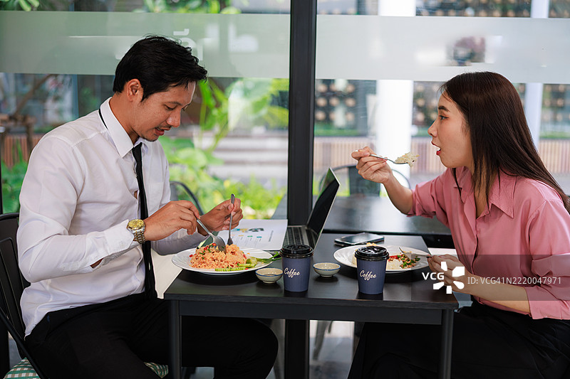 两位亚洲商务专业人士在现代餐厅进行轻松的午餐会议。捕捉工作场所文化、合作与职业网络的精髓，展现午间休息时光。图片素材