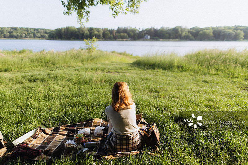 在宁静湖畔野餐的陌生女性图片素材