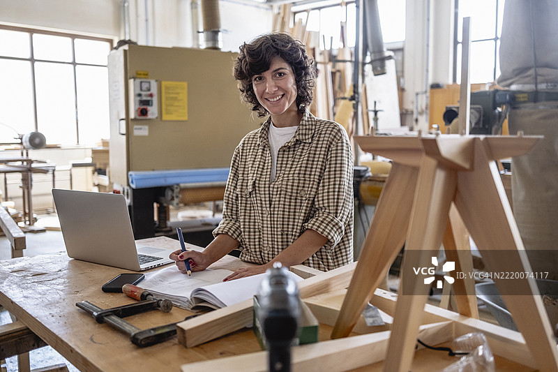 中年女性木匠在阳光明媚的工作室管理业务运营图片素材