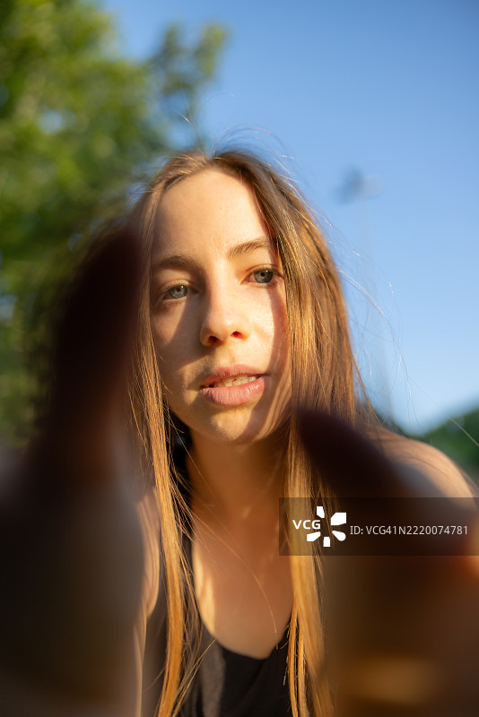 年轻女性在自然中触摸设备屏幕，蓝色眼睛闪烁。图片素材