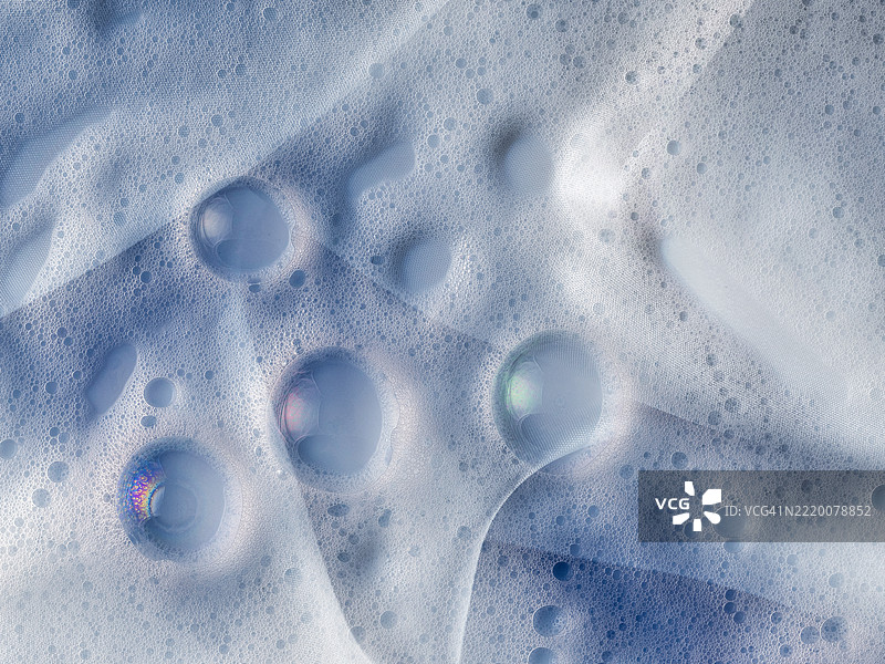 蓝色调的丝绸布料上混合着浮雕泡沫和肥皂泡。图片素材