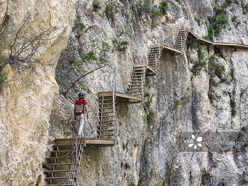 冒险旅游，一名女性正在攀爬嵌入峡谷岩壁的木栈道。雷尤桥（Pasarela de Relleu）图片素材