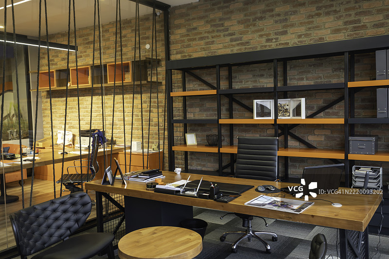 现代商业工作空间内空旷的当代工业办公室，砖墙、木质桌子和极简主义书架。图片素材