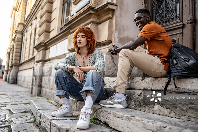 年轻朋友们坐在历史悠久的石建筑外的台阶上图片素材