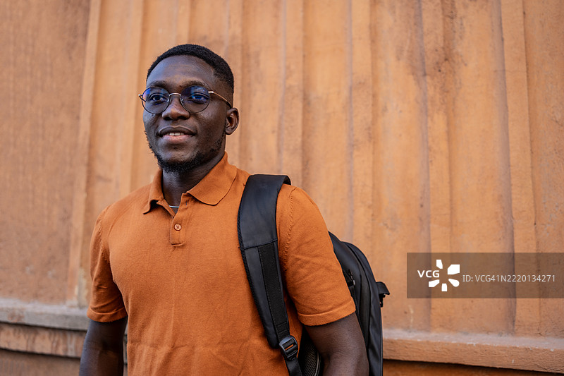 戴眼镜的年轻男子在城市户外环境中背着背包图片素材