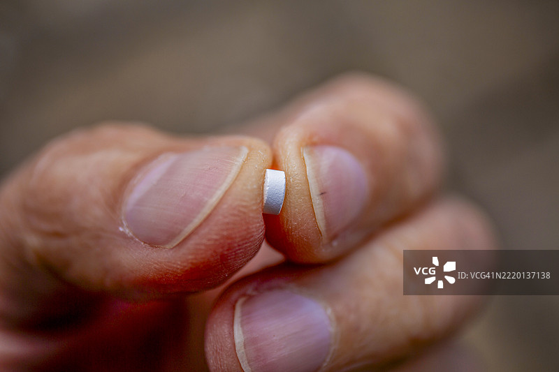 手指尖夹着的β-阻滞剂药丸特写图片素材