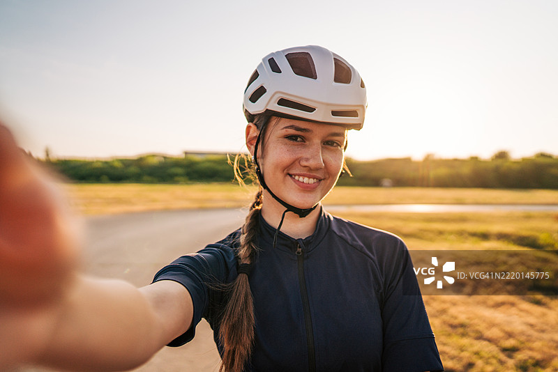 微笑的女性骑自行车者在训练后自拍图片素材