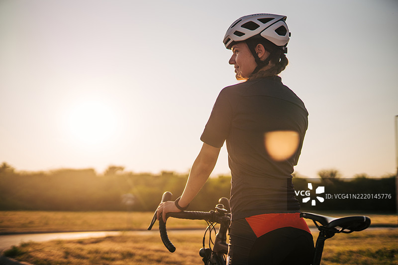 女性骑自行车者在骑行训练后享受日落美景图片素材