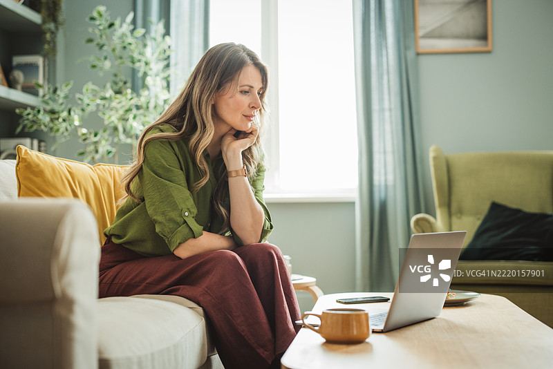 成熟的女性在家中使用笔记本电脑图片素材